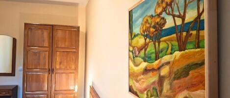 Une chambre à coucher avec un lit, une armoire en bois et un tableau représentant un paysage.
