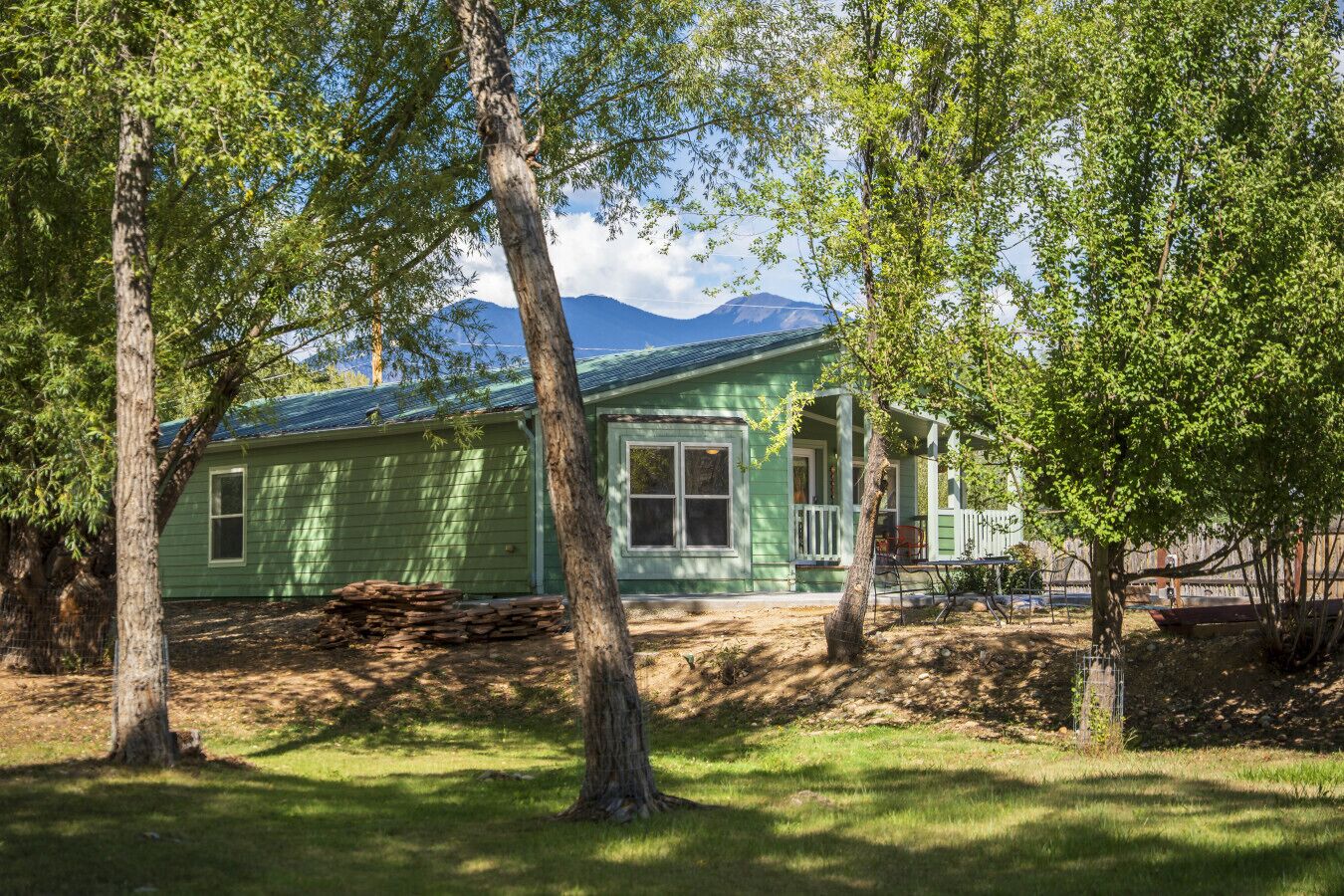 Ein grünes Haus mit Veranda und einem Berg im Hintergrund.