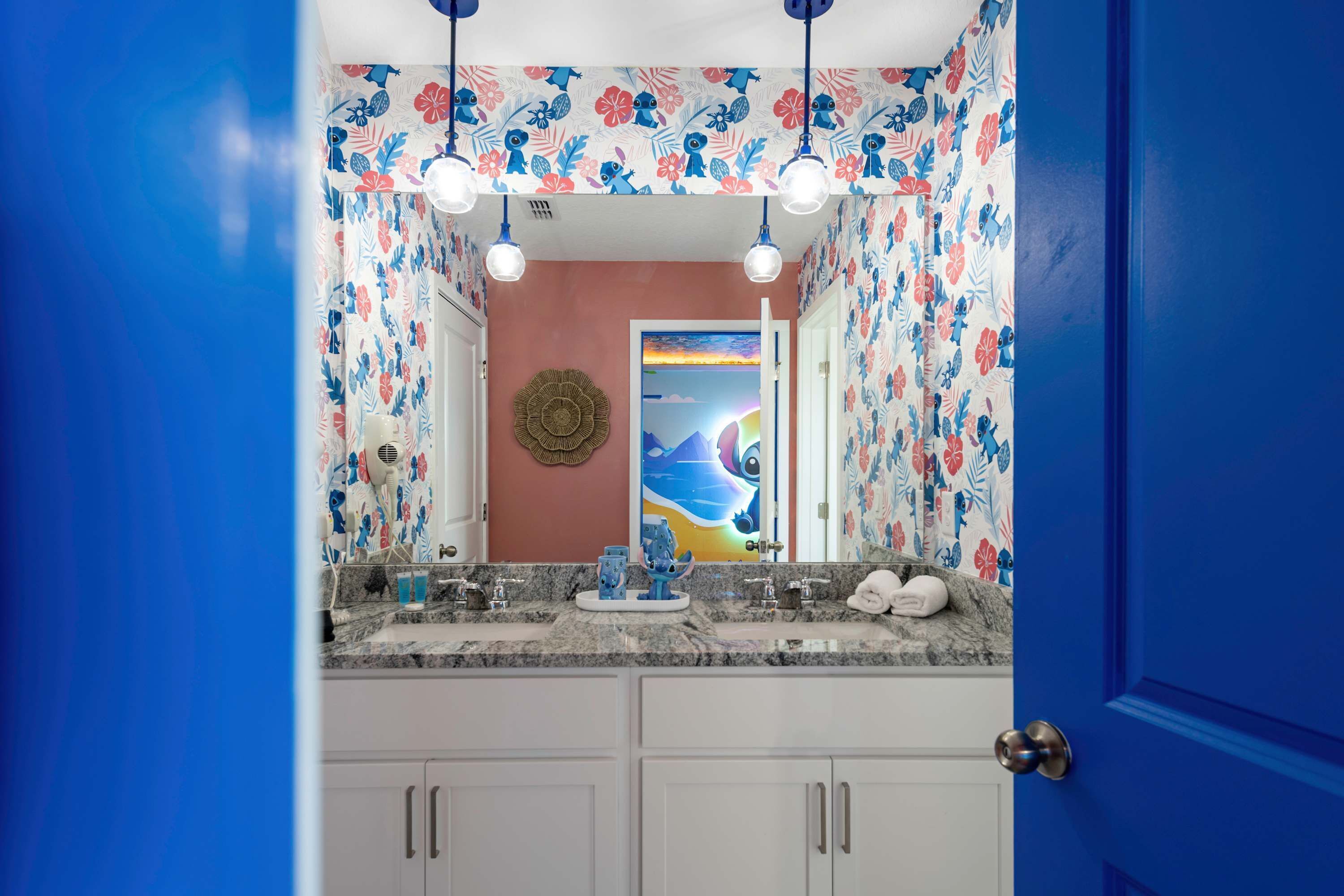 A bathroom with a floral shower curtain, a round mirror, and a sink with a marble countertop.