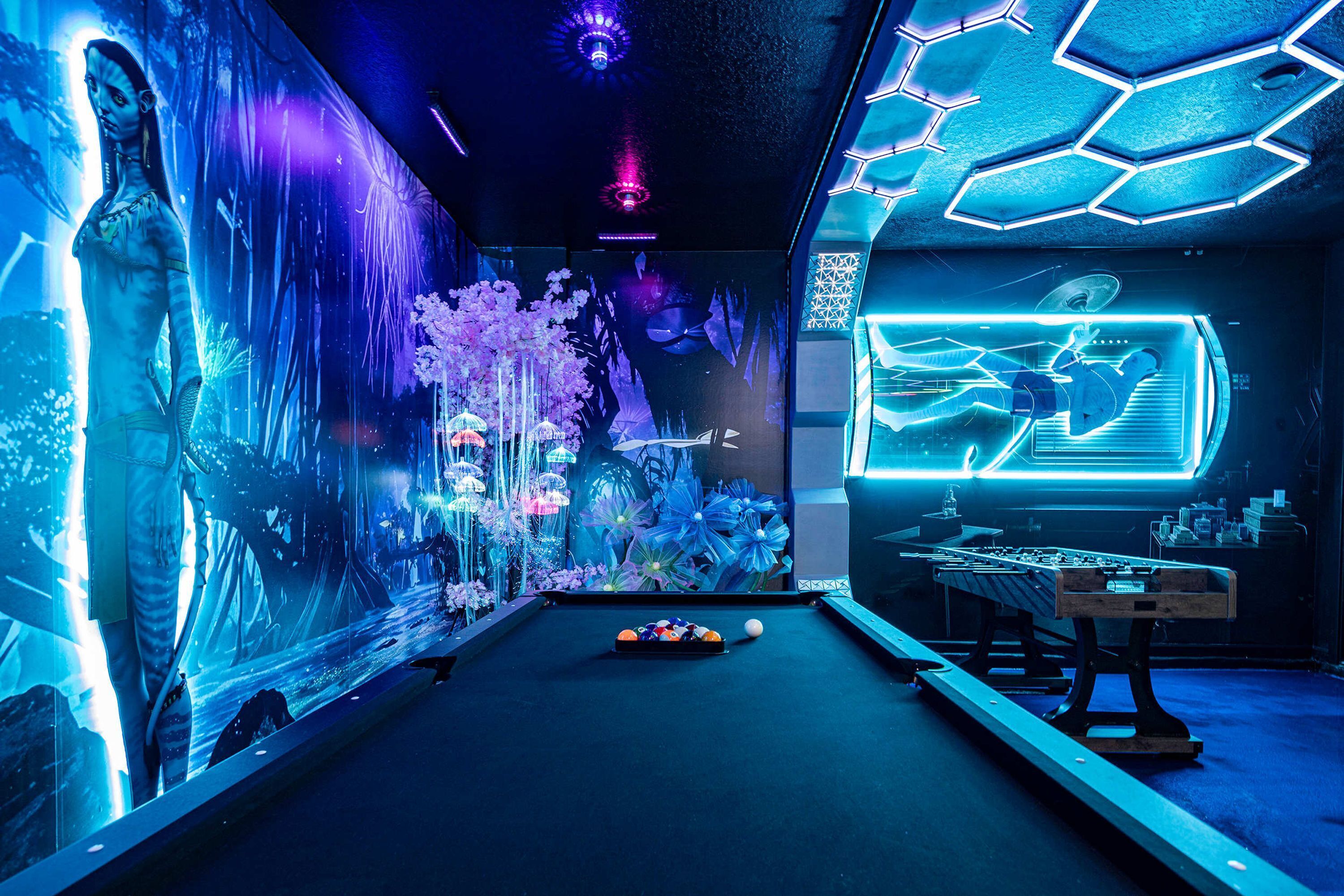 A pool table with a neon-lit room, including a large screen displaying a game and a futuristic design.