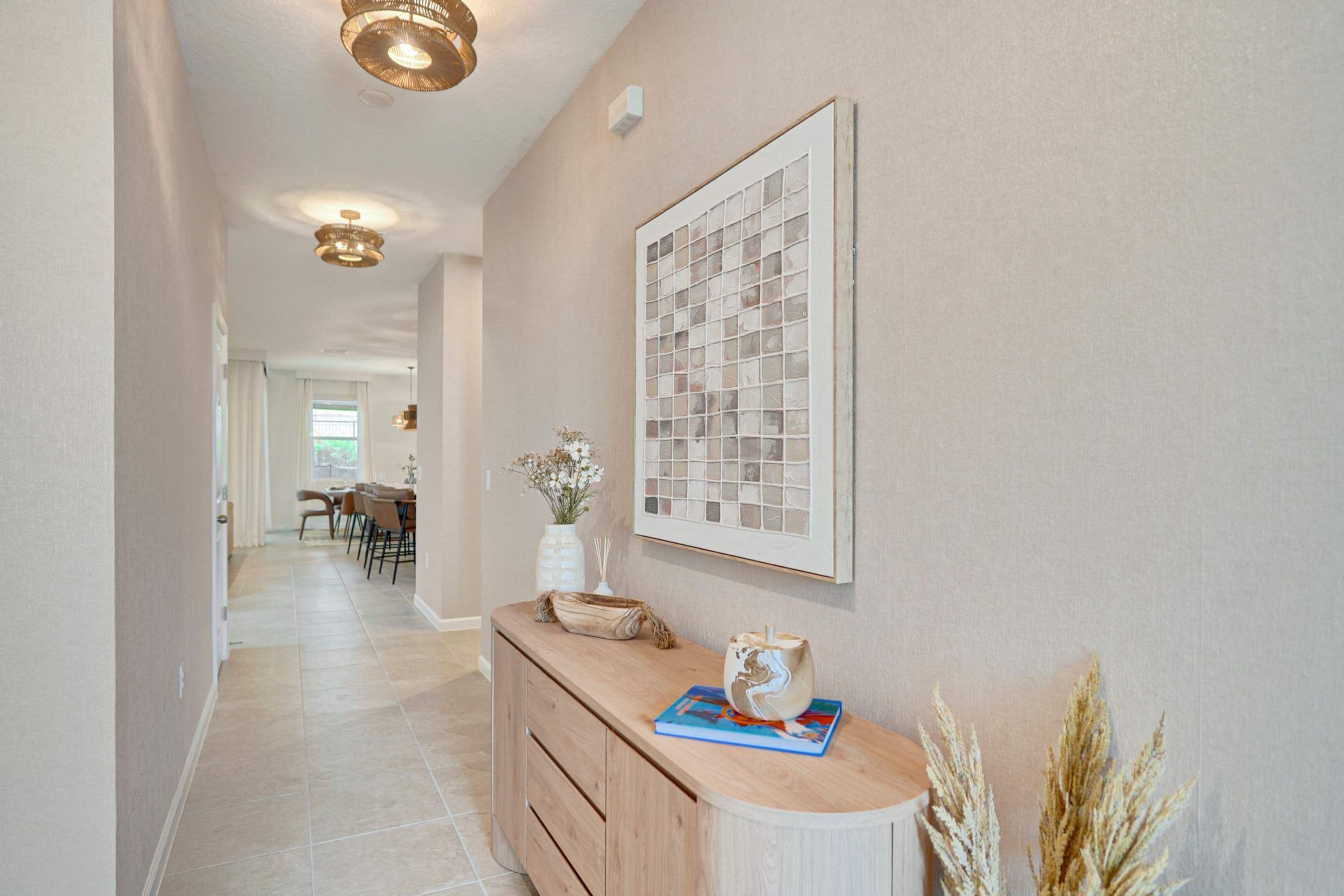A hallway with a wooden console table, a framed artwork, and decorative plants.