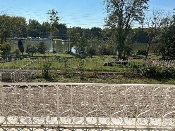 A view of a park with a lake, a fenced area, and a metal railing in the foreground.