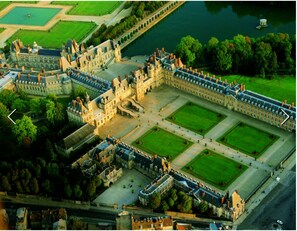 An aerial view of a large, historic building complex with multiple courtyards and a river in the background.