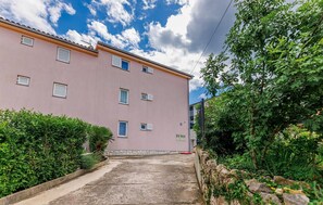 A pink building with multiple windows and a concrete pathway leading to the entrance. - Lovely apartment in Dobrinja with WiFi (Malinska)
