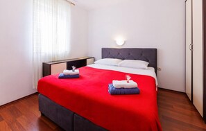 A hotel room with a bed, a nightstand, a wall-mounted light, and a window with curtains. - Lovely apartment in Dobrinja with WiFi (Malinska)