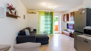 A compact living space with a sofa, a small table, a TV, and a refrigerator. - Lovely apartment in Dobrinja with WiFi (Malinska)