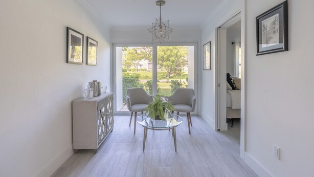Un hall d’entrée spacieux, avec une table basse en verre, deux chaises et un luminaire décoratif.