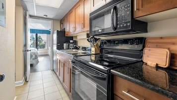Una cocina con armarios de madera, estufa de acero inoxidable, microondas y un lavaplatos.