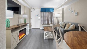 Ein gemütliches Zimmer mit Kamin, Fernseher, einer Couch und einem Esstisch.