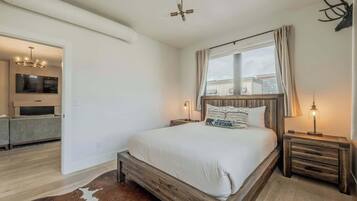 Un dormitorio con una cama de madera, un tapiz de cuero de vaca, un televisor en la habitación contigua y un ventilador de techo.