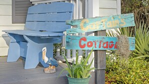 Eine hölzerne Bank und ein Schild mit dem Schriftzug 'Captain's Corner' auf einer Veranda.