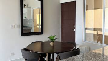 Uma área de jantar moderna com uma mesa redonda, cadeiras, um vaso de planta e um espelho grande na parede.