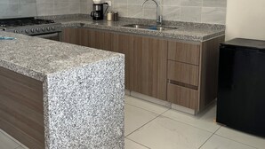 Een moderne keuken met granieten aanrechtbladen, een roestvrijstalen fornuis en houten keukenkastjes.