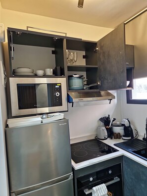 Eine moderne Küche mit eingebauter Mikrowelle, Herd und Backofen, Edelstahlgeräten und einer kompakten Anordnung.