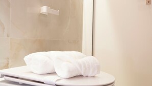 A modern bathroom with a white toilet, a towel on the seat, and a marble wall. - Mini apartments in the center of Catania (Catania)