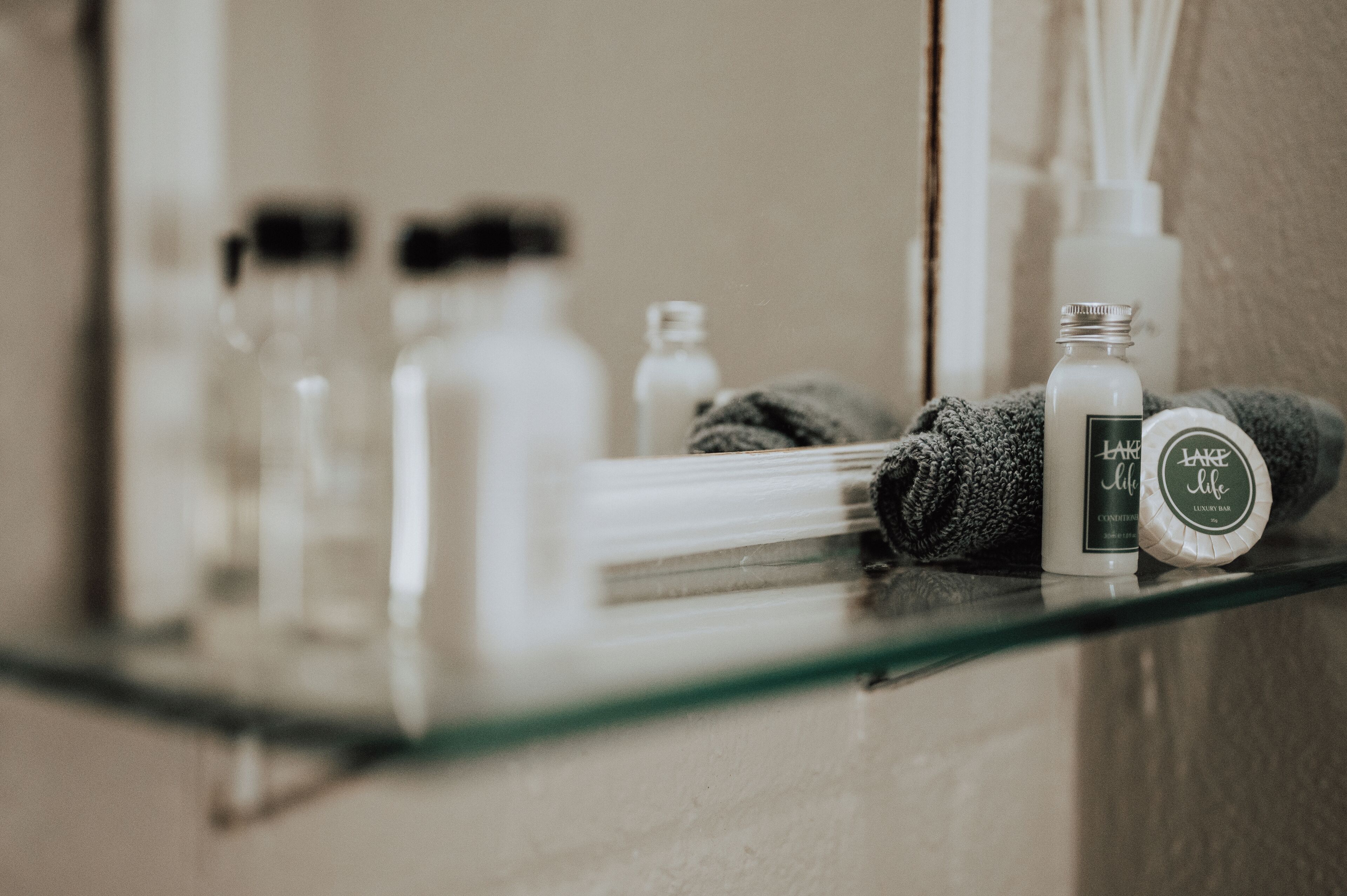 Une étagère de salle de bain contenant des articles de toilette, notamment un flacon de lotion, un savon et une serviette.