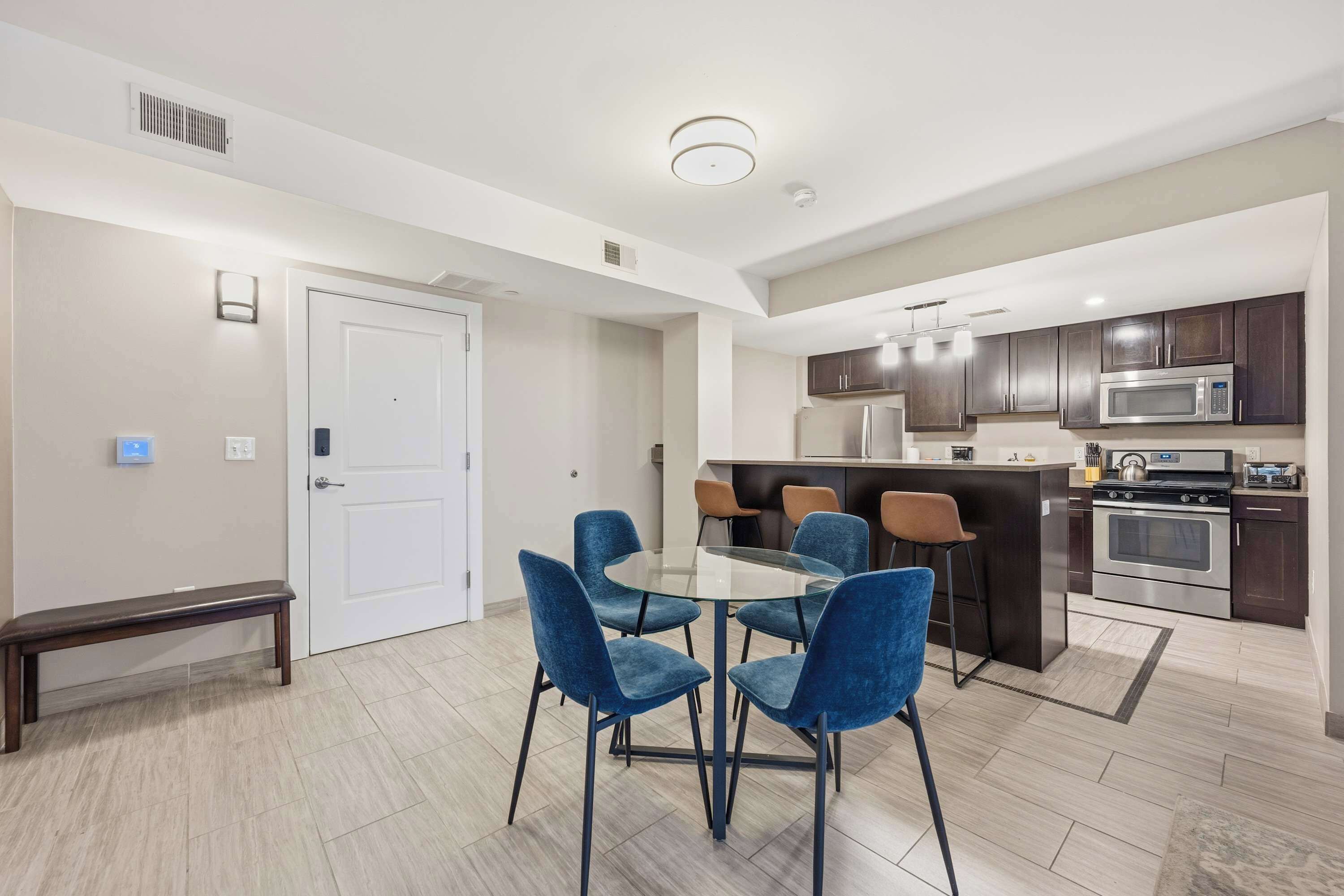 A modern kitchen with dark cabinets, a stainless steel refrigerator, and a microwave.