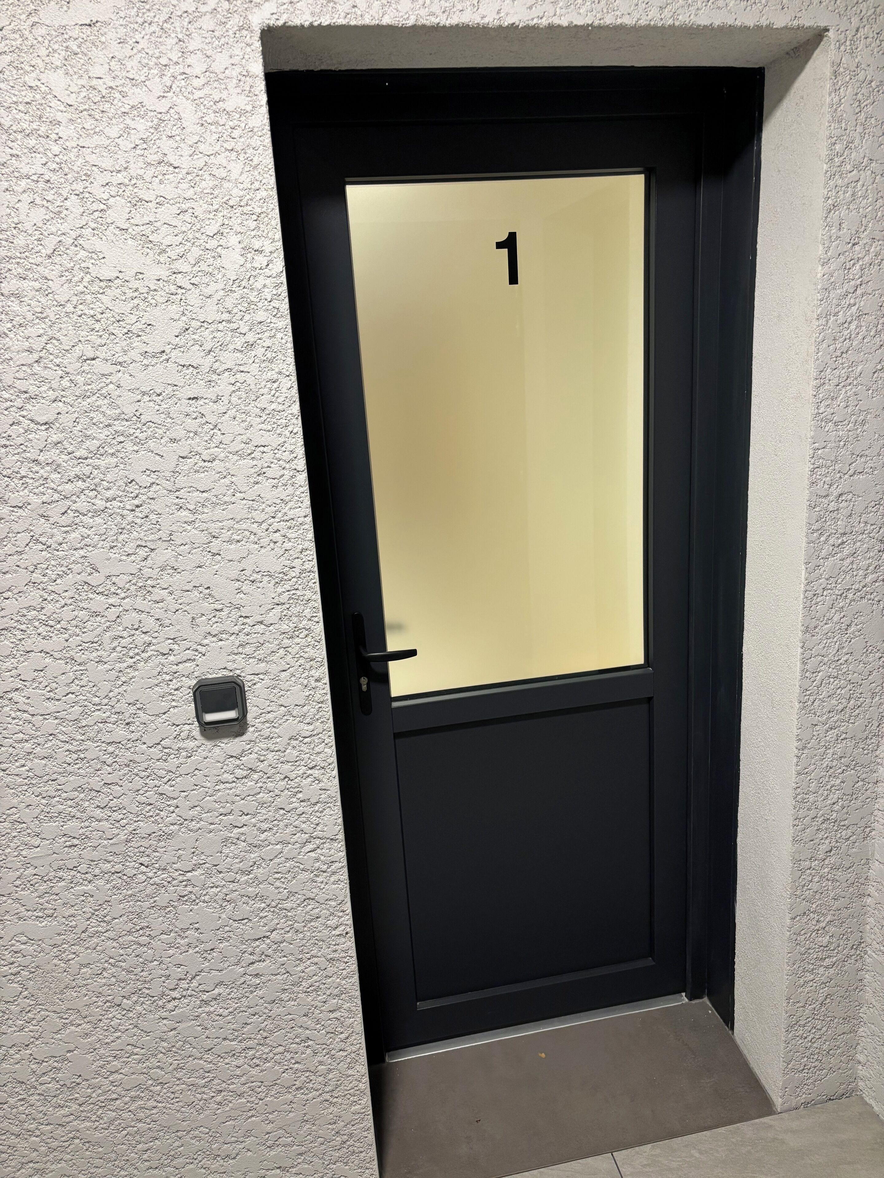 A door with a number 1 sign, a glass panel, and a black frame.