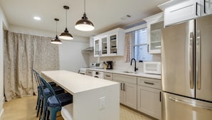 A modern kitchen with white cabinets, stainless steel appliances, and pendant lighting. - Walk to Metro & Downtown! Cozy Silver Spring Apt (Silver Spring)