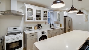 A modern kitchen with white cabinets, a stainless steel range hood, a built-in oven, a dishwasher, a microwave, and a refrigerator. - Walk to Metro & Downtown! Cozy Silver Spring Apt (Silver Spring)