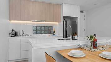 A modern kitchen with white cabinetry, a built-in island, and a dining area with a wooden table.