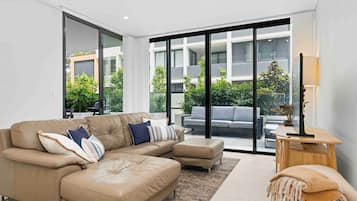 A modern living room with a beige sectional sofa, a grey sofa, and a wooden side table with a lamp.