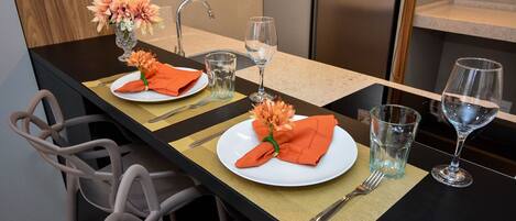 Un comptoir de cuisine aménagé en coin repas, avec deux assiettes, un vase de fleurs et deux verres à vin.