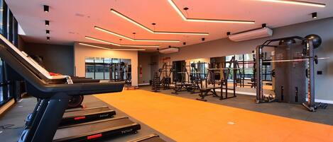 Een moderne sportschool met loopbanden, krachtapparaten en een grote spiegel.