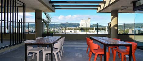 A rooftop terrace with outdoor seating, a pergola, and a view of the cityscape.