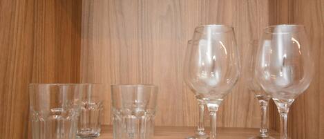 Una estantería de madera con cuatro copas de cristal para vino y dos copas de cristal para agua.