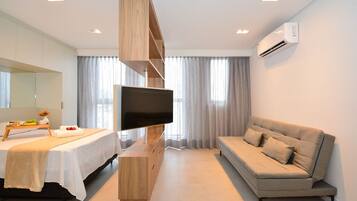Una habitación de hotel moderna con una cama, un sofá, un televisor y un mueble de entretenimiento de madera.