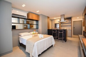 Et moderne hotelværelse med seng, skrivebord og tekøkken.