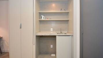 A compact bathroom with a sink, shelves, and a small cabinet.