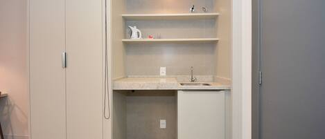 A compact bathroom with a sink, shelves, and a small cabinet.