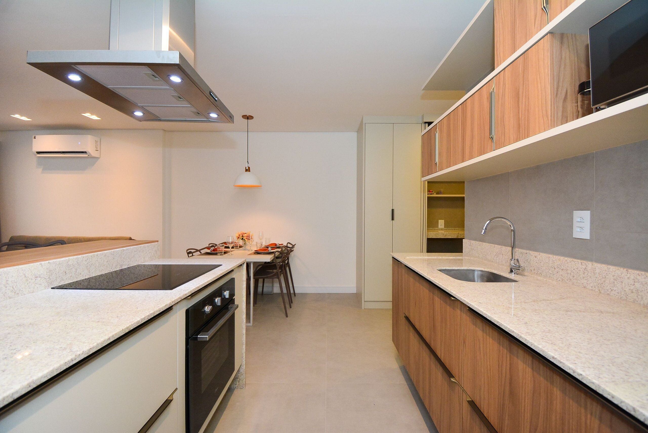 Una cocina moderna con horno integrado, un lavamanos y una zona de comedor con mesa y sillas.
