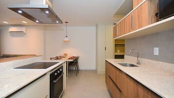 Una cocina moderna con horno integrado, un lavamanos y una zona de comedor con mesa y sillas.