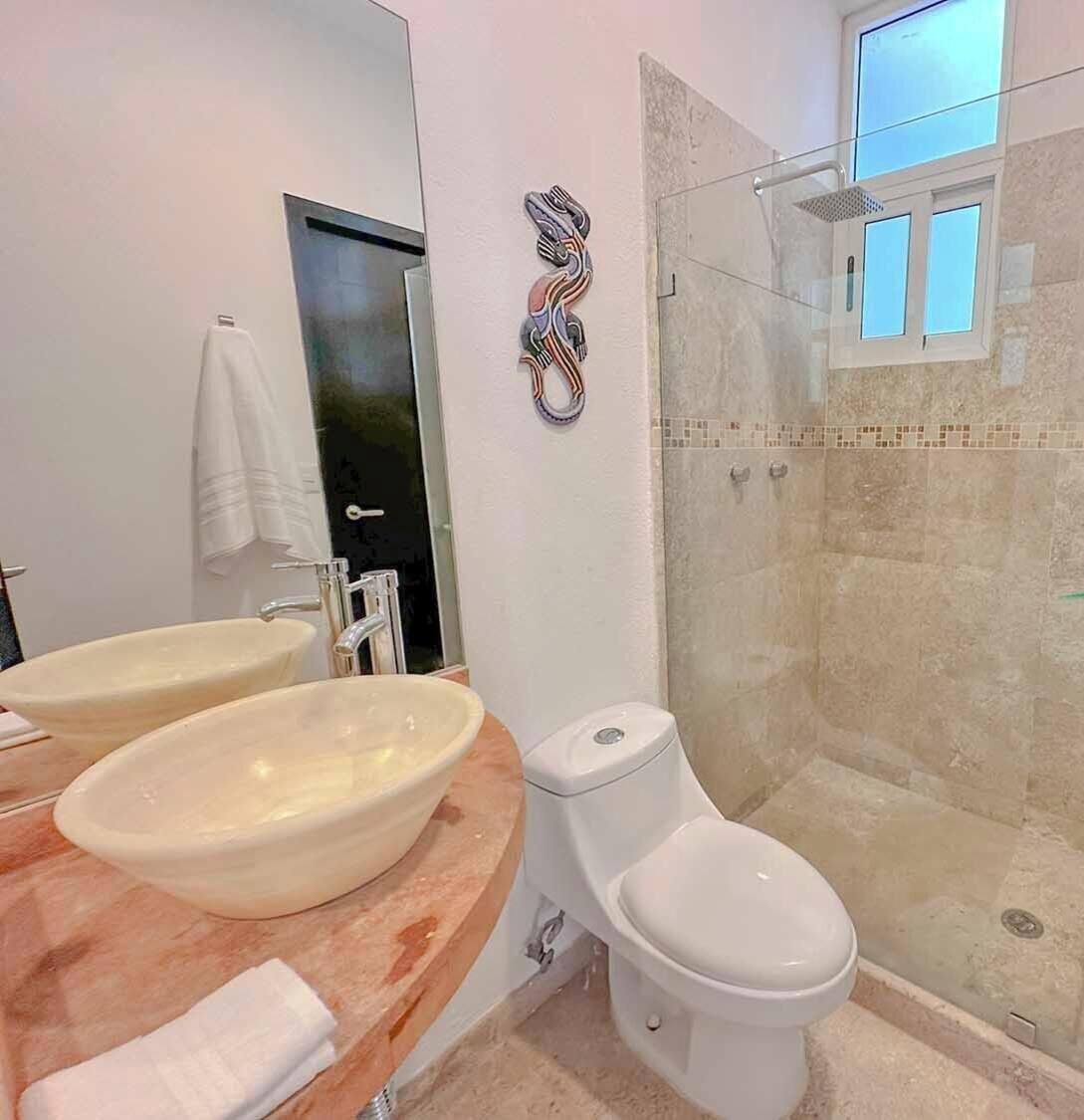 Une salle de bain moderne avec deux lavabos, des toilettes et une douche à parois de verre.