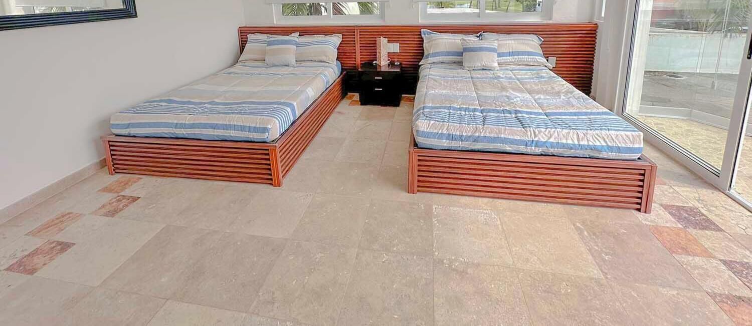 Une chambre avec deux lits, une table de chevet et une grande fenêtre.