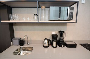 Een keuken met een spoelbak, koffiezetapparaat, blender en magnetron.
