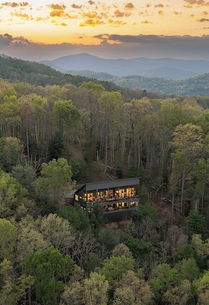Ein modernes Haus, umgeben von dichtem Wald, mit freiem Blick auf die umliegende Landschaft.