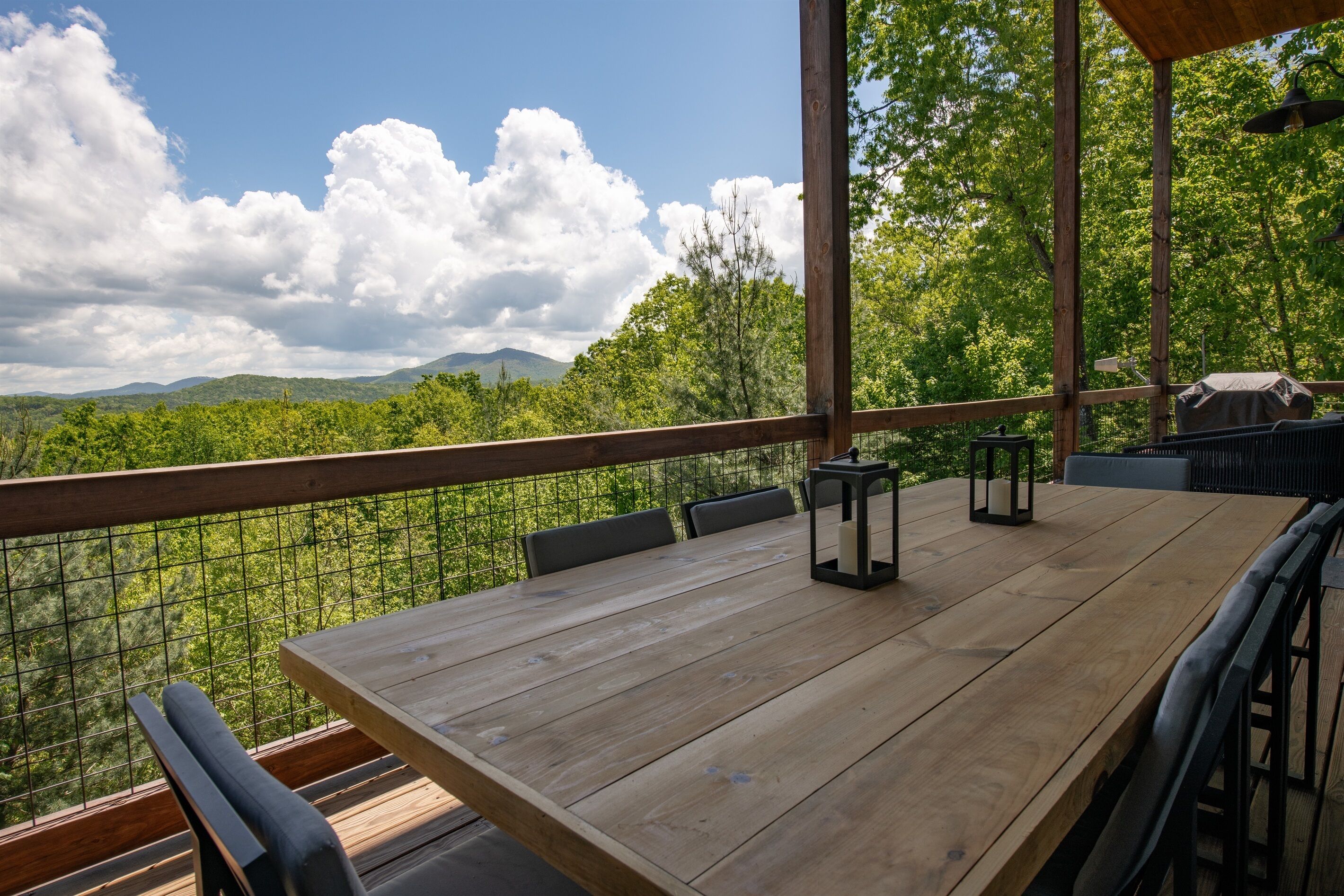 A wooden deck with a table and chairs, overlooking a mountainous landscape.