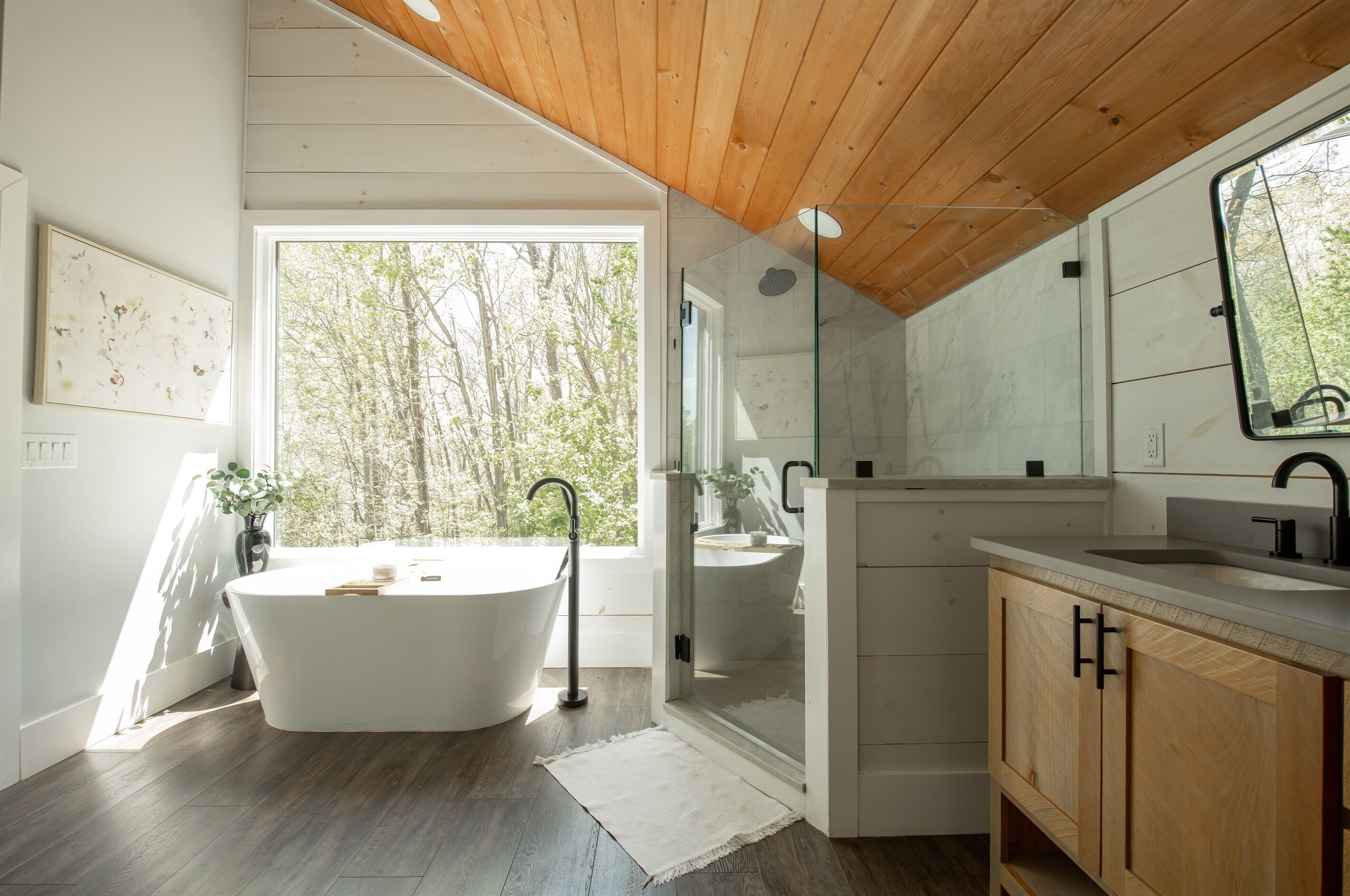 A modern bathroom with a freestanding bathtub, a glass-enclosed shower, and a large mirror.