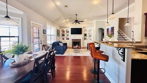 A spacious living area with a dining table, chairs, a sofa, and a kitchen area with a bar.