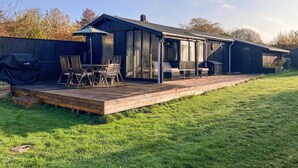 Une maison moderne dotée d’une terrasse, d’un espace salon extérieur et d’un coin barbecue.