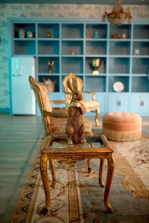 A room with a wooden coffee table, a patterned rug, and a blue shelving unit in the background. - Cottage for 2 | IN TOWN | Firepit+Pool+Pickleball (Round Top)