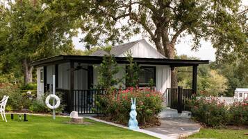 A house with a covered porch, a small garden with pink flowers, and two inflatable rings on the grass.