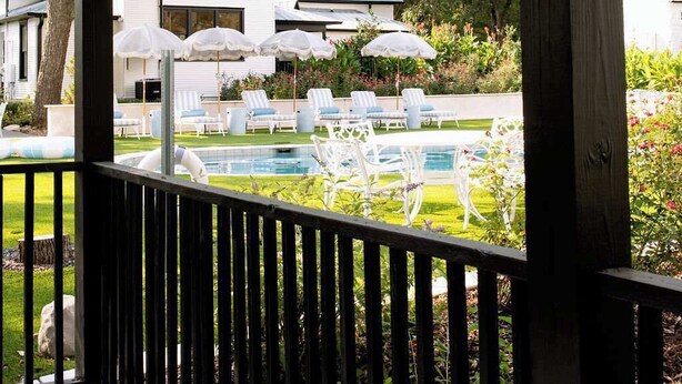 Un espace extérieur abrité comprenant une piscine, des chaises longues et des parasols.