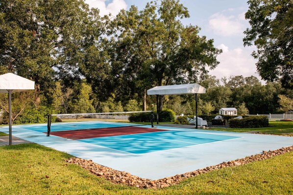 An outdoor tennis court with a net, surrounded by trees and a white gazebo. - Pool + Pickleball + Firepit | IN TOWN | Sleeps 8 (Round Top)