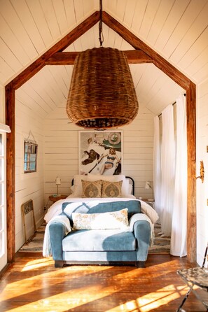 A bedroom with a bed, a hanging basket, a wall-mounted picture, and a wooden floor. - Pool + Pickleball + Firepit | IN TOWN | Sleeps 8 (Round Top)