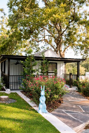 A covered outdoor area with a stone pathway leading to a building with a white facade and dark trim.